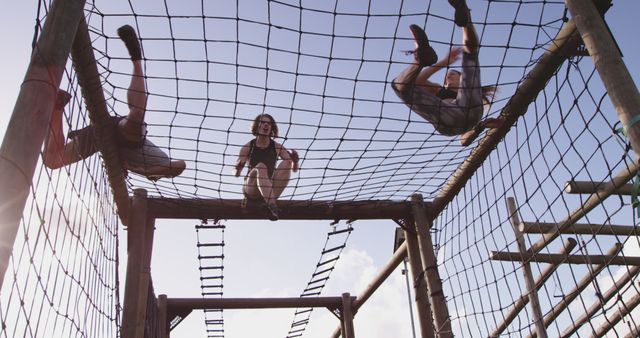 Group of individuals scaling an outdoor rope obstacle course in bright daylight. Ideal for use in marketing material for outdoor adventure parks, team-building events, fitness training programs, or lifestyle blogs focusing on healthy activities and recreation. Emphasizing teamwork, physical activity, and the challenge of outdoor sports.