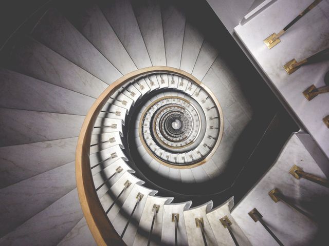 Captivating spiral staircase viewed from above with golden handrails and marble steps. Perfect for use in architectural magazines, interior design portfolios, or architectural planning presentations to showcase elegant staircase designs.