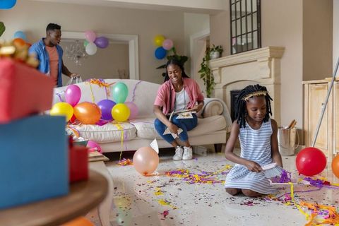 African american family cleaning up after colorful birthday party in cozy living room