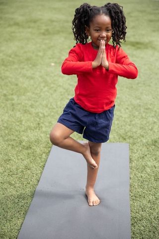 Young African American Girl Practicing Yoga Balancing on Mat