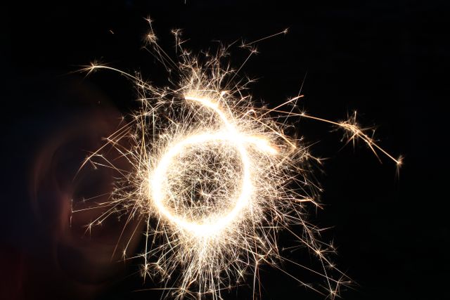 Close-up view of hand holding sparkler against dark background. Ideal for themes related to celebrations, parties, joy, and festive occasions. Perfect for marketing materials, event promotions, and holiday greeting cards.