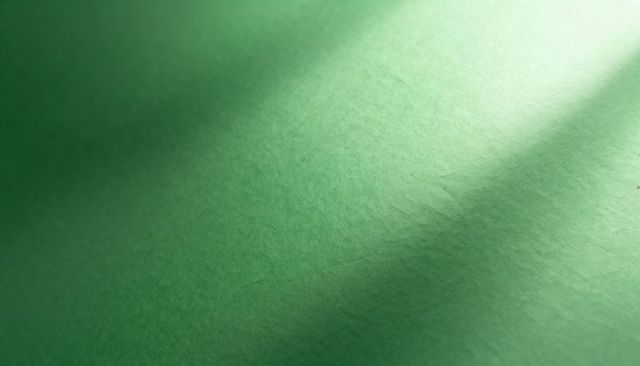 Green textured paper close-up showing diagonal shadow soft highlight and crease