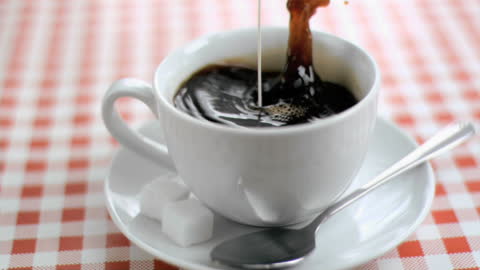 Milk Splash in Coffee Cup on Checkered Tablecloth