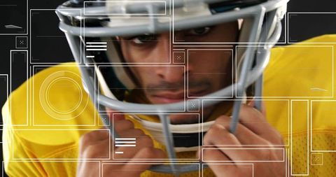 Gripping facemask football player adjusting chinstrap in yellow jersey with tech overlays