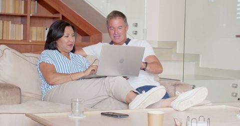 Senior Couple Using Laptop on Sofa in Cozy Living Room