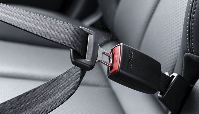 Seat belt buckle clicking into place on perforated leather car interior for safety