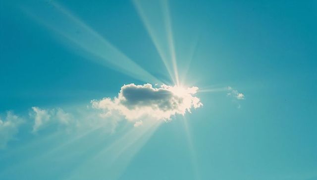 Sun Rays Illuminating Cloud in Clear Blue Sky