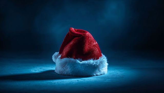 Red Velvet Santa Hat on Dark Floor with Blue Spotlight and Dramatic Shadow