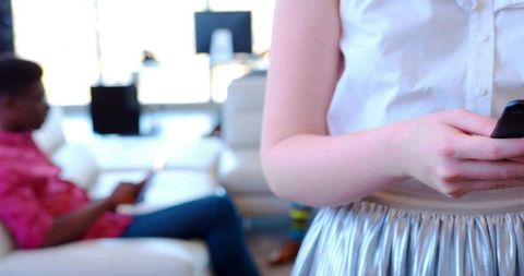 Woman holding smartphone in modern office lounge area