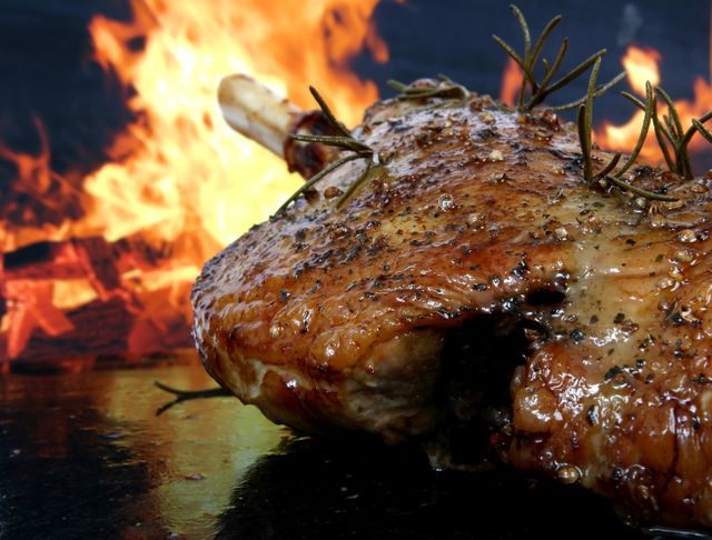 Grilled meat roast seasoned with herbs with flames in the background. Perfect for BBQ, culinary, grill, summer cookouts, restaurant promotions, fine dining imagery.