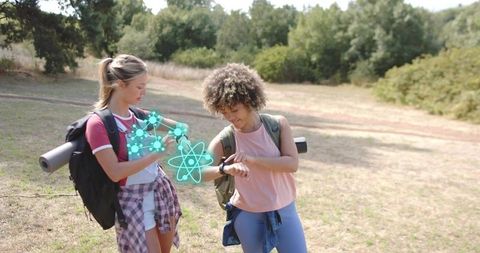 Female hikers checking smartwatch with augmented reality fitness hologram in sunny outdoor trail