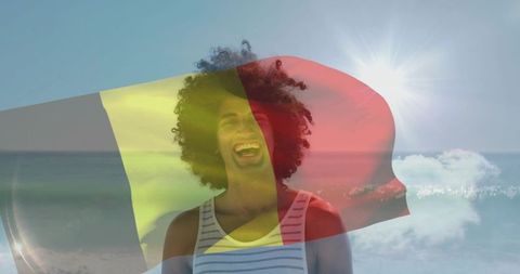 Laughing man standing on sunlit beach with tricolor flag overlay and ocean horizon