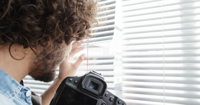 Man Peering Through Blinds with Camera in Hand - Download Free Stock Images Pikwizard.com