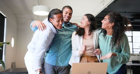 Diverse Colleagues Celebrating Success with Lively Discussion Around Laptop