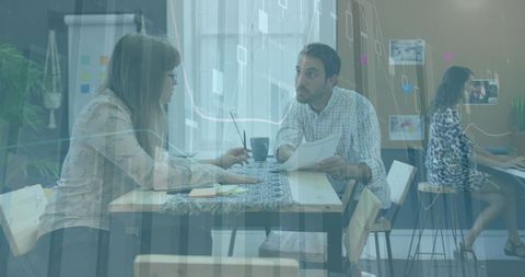 Diverse Team Discussing Business Reports with Data Overlay in Office Setting