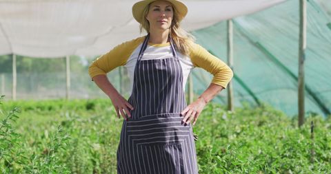 Confident Female Gardener in Greenhouse Wearing Apron
