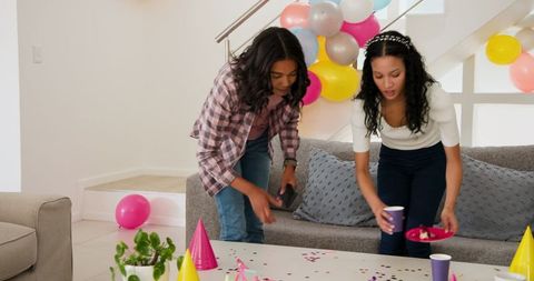 Women setting up colorful birthday party decorations