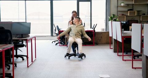 Colleagues Playfully Spin in Scenic Modern Workspace, Laughing and Bonding