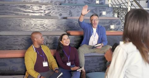 Diverse workshop participants raising hand and taking notes on tiered seating