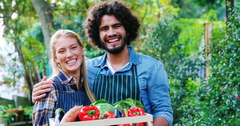 Smiling Farmers Holding Freshly Harvested Vegetables Outdoors