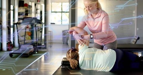 Physical therapist guiding patient through assisted shoulder stretch in daylight clinic