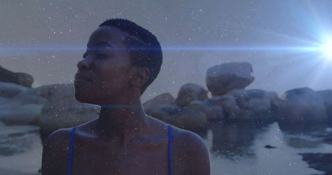 Woman at Rocky Shoreline Sees Morning Light Reflection