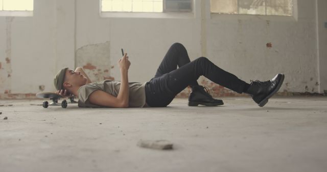 Young Man Lying on Skateboard Using Smartphone in Industrial Space - Download Free Stock Images Pikwizard.com