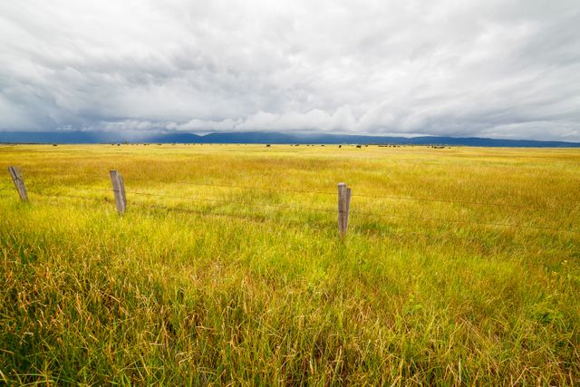Stormy Sky Over Vast Countryside Field with Fence - Download Free Stock Photos Pikwizard.com
