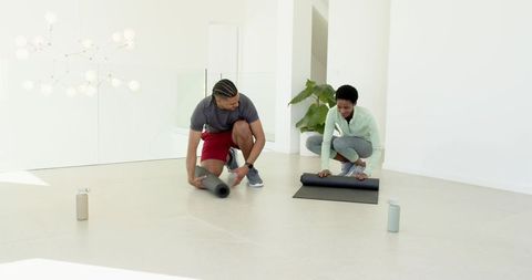 Diverse Duo Preparing Yoga Mats in Modern Fitness Studio