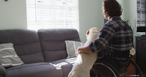 Happy disabled man enjoying time with pet dog at home