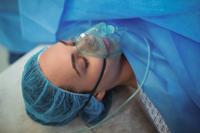 Female patient with oxygen mask in operation theater at hospital