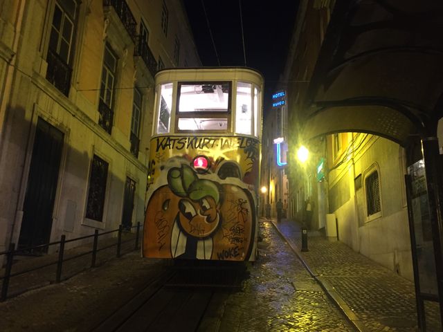 Graffiti-covered tram in Lisbon at night on a narrow street - Download Free Stock Photos Pikwizard.com