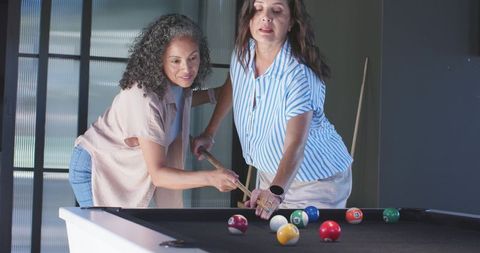 Women guiding pool shot teaching billiards and sharing friendship in game room