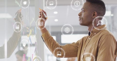 Businessman analyzing financial data on whiteboard with digital icons