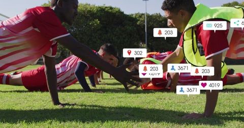 Soccer players doing plank reach drill with social media notification overlays on grass