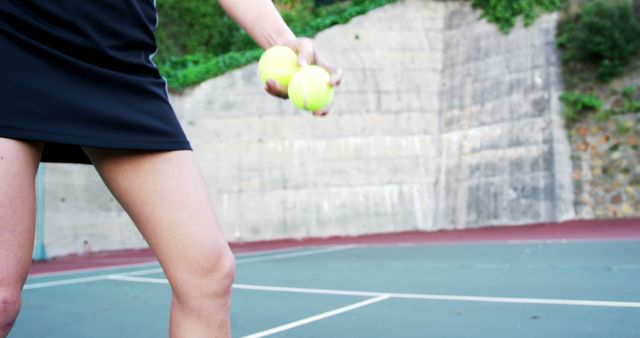 Female tennis player holds tennis balls on outdoor court. Suitable for sports, fitness, and active lifestyle themes or content.