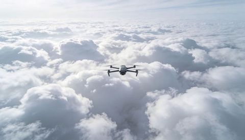 Compact quadcopter drone soaring above endless cumulus clouds showcasing camera gimbal