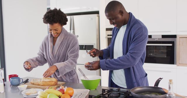 Image of happy african american couple preparing breakfast together in kitchen. Love, relationship and spending quality time together concept.