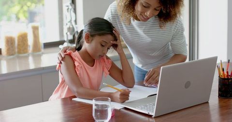 Mother Assisting Daughter with Schoolwork in Modern Kitchen