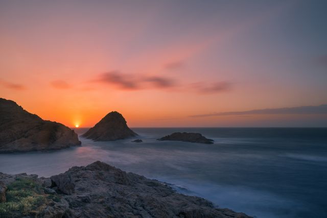 Serene Sunset Over Rocky Coastline with Calm Sea - Download Free Stock Photos Pikwizard.com