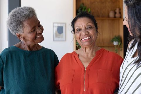 Diverse older women sharing laughter and companionship in warm sunlit living room