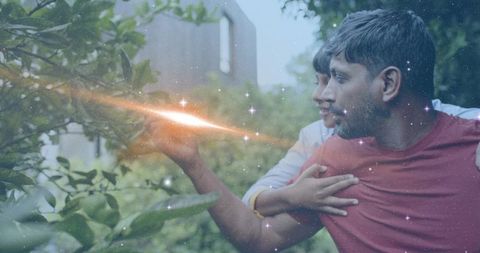 Father and son reaching through garden leaves with magical glow and tender embrace
