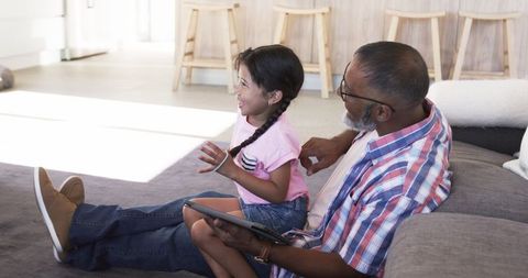 Grandfather and Granddaughter Sharing Moment on Digital Tablet