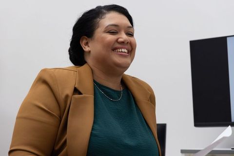 African american professional laughing in modern office wearing mustard blazer and teal top