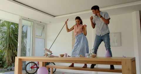 Joyful couple cleaning together at home, embracing daily chores with energy