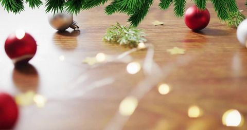 Cozy christmas bokeh tabletop with evergreen garland, red and silver baubles, fairy lights