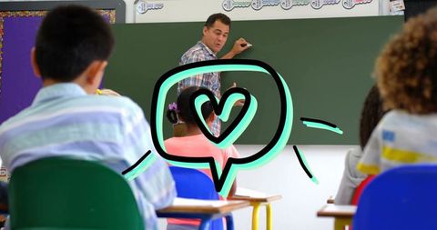 Teacher writing on chalkboard teaching lesson to engaged elementary students