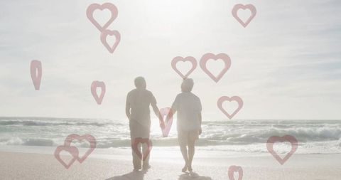 Elderly couple walking hand in hand along tranquil seaside