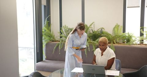 Collaborative businesswomen engaging in office meeting on laptop