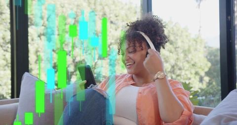Young woman relaxing with headphones and phone while viewing financial candlestick chart overlay